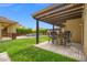 A backyard patio with a pergola and outdoor seating overlooks a sparkling pool and lush landscaping at 6335 Iginlas Goal Ave, Las Vegas, NV 89131