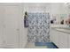 Bright bathroom with shower featuring a blue floral curtain, single vanity and linen closet at 664 Foam Flower Ln, Henderson, NV 89015