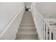 Bright staircase featuring neutral carpet and white railing leading to the upper level, enhancing the home's modern appeal at 664 Foam Flower Ln, Henderson, NV 89015