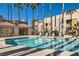 Relaxing community pool features lounge chairs and tall palm trees under a clear, blue sky at 6853 Tamarus St # 202, Las Vegas, NV 89119