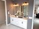 Elegant Primary bathroom with double sinks, white cabinetry, and modern lighting fixtures at 933 Hunter Shores Ave, North Las Vegas, NV 89084