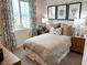 A well-lit bedroom featuring a picture window with patterned curtains and minimalist decor at 933 Hunter Shores Ave, North Las Vegas, NV 89084