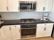 Modern kitchen with stainless steel oven and microwave, white cabinets, and dark countertops at 933 Hunter Shores Ave, North Las Vegas, NV 89084