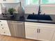 Close-up of kitchen sink with stainless steel dishwasher, white cabinets, and modern faucet at 933 Hunter Shores Ave, North Las Vegas, NV 89084