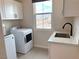 A well-lit laundry room with new white washer and dryer, plus a deep utility sink at 933 Hunter Shores Ave, North Las Vegas, NV 89084