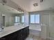 Bathroom featuring dual sinks, dark cabinets, and a separate tub and shower at 9604 Vital Crest St, Las Vegas, NV 89123