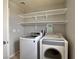Efficient laundry room including modern washer and dryer units, with overhead shelving for supplies at 9604 Vital Crest St, Las Vegas, NV 89123