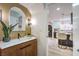 Stylish half bathroom showcasing a wooden vanity, arched mirror, and a glimpse into the updated kitchen at 10009 Coral Sands Dr, Las Vegas, NV 89117
