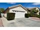A two-car garage door with driveway and manicured bushes in front of this charming single Gathering home at 10025 Catseye Cove Ct, Las Vegas, NV 89183
