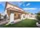 Backyard showcasing a covered patio with artificial grass at 10166 Monks Hood Ct, Las Vegas, NV 89183