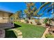 Manicured backyard featuring artificial turf, custom stonework, and a covered patio area at 1574 Livingston Dr, Henderson, NV 89012
