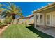 Well-maintained backyard featuring artificial grass, a mature palm tree, and a covered patio area, perfect for outdoor relaxation at 1574 Livingston Dr, Henderson, NV 89012