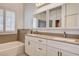 Dual sink vanity in a bathroom featuring white cabinets, tub, and shuttered window at 1574 Livingston Dr, Henderson, NV 89012