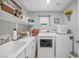 Bright laundry room with white appliances, sink, ample counter space, and storage shelves at 2021 Royal Gardens Pl, North Las Vegas, NV 89084