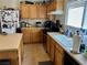 Compact kitchen with wood cabinets, black appliances, and tile flooring near counter at 2130 Dragonslayer Ave, Las Vegas, NV 89183