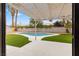 A backyard featuring a sparkling pool, artificial turf, a white pergola, and desert landscaping at 2620 E Harmon Ave, Las Vegas, NV 89121