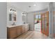 Bright bathroom featuring dual sinks, wood cabinets, orange door and wood-look floors at 2620 E Harmon Ave, Las Vegas, NV 89121
