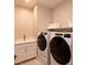 Modern laundry room with a sink, storage cabinets, and high-efficiency washer and dryer at 2650 Skylark Trail St, Henderson, NV 89044