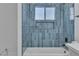 Modern shower features blue tiling, white tub, glass enclosure, and recessed niche for storage at 2721 Bruce Cir, North Las Vegas, NV 89030