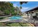 Inviting backyard with pool, tile patio, and a covered outdoor seating area with landscaping and trees at 3151 Coachlight Cir, Las Vegas, NV 89117