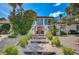Inviting two-story home with mature trees, manicured landscaping, and a charming walkway leading to a red entryway at 3151 Coachlight Cir, Las Vegas, NV 89117