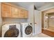 Modern laundry room featuring wooden cabinets, tiled floors, and modern washer and dryer at 3151 Coachlight Cir, Las Vegas, NV 89117