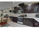 Modern kitchen showcasing stainless steel appliances, dark cabinets, and open layout to living area at 3707 Paseo De Paz Ave, Las Vegas, NV 89115
