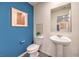 The powder room has a white pedestal sink, toilet, and decor in front of a blue painted accent wall at 4839 Orchid Ridge Ave # 96, Las Vegas, NV 89141