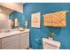 Bright bathroom with blue accent wall, white vanity, framed art, and checkered towels at 4839 Orchid Ridge Ave # 96, Las Vegas, NV 89141