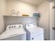 Neat laundry room with white washer and dryer and open shelving for storage at 4839 Orchid Ridge Ave # 96, Las Vegas, NV 89141