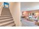 View of staircase and living room with sofa, chair, dining room table and chairs, and peach colored accent wall at 4839 Orchid Ridge Ave # 96, Las Vegas, NV 89141