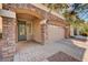Welcoming home entrance with stone pillars, arched entry, and a paver driveway leading to a two-car garage at 5239 Tartan Hill Ave, Las Vegas, NV 89141