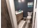 View of remodeled bathroom with modern gray plank flooring, white vanity and toilet, and navy walls at 53 Grossinger Ct, Henderson, NV 89074