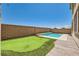 This backyard features a sparkling pool, putting green, wood deck, and block wall fencing for privacy at 5920 Big Horn View St, North Las Vegas, NV 89031