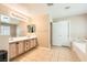 Bathroom features a double sink vanity, tile floors, a soaking tub, and decorative lighting at 5920 Big Horn View St, North Las Vegas, NV 89031