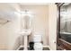 Half bathroom features a pedestal sink, toilet, decorative mirror and wood cabinet at 5920 Big Horn View St, North Las Vegas, NV 89031