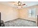 A view of a sparsely furnished bedroom, with carpeting, a window, and a ceiling fan at 5920 Big Horn View St, North Las Vegas, NV 89031