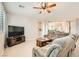 Spacious living room with a sectional sofa, ceiling fan, and large windows with shutters at 5920 Big Horn View St, North Las Vegas, NV 89031