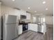 Well-lit kitchen features stainless steel appliances, white cabinets and an island overlooking the living area at 6719 Violet Cascade Ave, Las Vegas, NV 89156