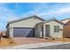 Single-story house featuring desert landscaping, a gray two-car garage door, and a tiled walkway at 6731 Lotus Vista Ct, Las Vegas, NV 89156