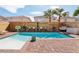 Beautiful in-ground pool with a brick surround, complemented by cozy seating and lush palm trees at 7566 Hope Valley St, Las Vegas, NV 89139