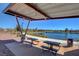 Community area with covered seating and picnic tables overlooking a calm lake under a blue sky at 759 Pickled Pepper Pl, Henderson, NV 89011