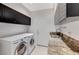 Laundry room with stainless steel washer and dryer, granite countertops, and cabinet storage at 8121 Castle Pines Ave, Las Vegas, NV 89113