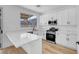 Modern kitchen featuring white cabinetry, stone countertops, stainless steel appliances, and wood look flooring at 8725 Russet Hills Ct, Las Vegas, NV 89147