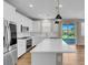 Bright, white kitchen with stainless steel appliances, island, and sliding door to the backyard at 880 Cirrus Cloud Ave, Las Vegas, NV 89138