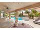 An inviting covered outdoor living space with a pool, spa, and comfortable seating area at 9615 Sedona Hills Ct, Las Vegas, NV 89147