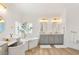 Well-lit primary bathroom features dual sinks, a soaking tub, wood-look floors, and modern decor at 9615 Sedona Hills Ct, Las Vegas, NV 89147