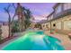 Backyard oasis featuring a sparkling pool, spa, covered patio, and mature trees at 9615 Sedona Hills Ct, Las Vegas, NV 89147