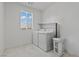 Laundry room with white washer, dryer, tile flooring, and a window at 9742 Toad Hollow St, Las Vegas, NV 89141