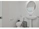 Powder room offers a pedestal sink, round mirror, and toilet at 9742 Toad Hollow St, Las Vegas, NV 89141